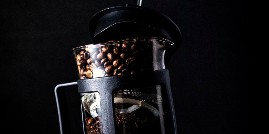 A French press filled with coffee, lit dramatically against a dark background
